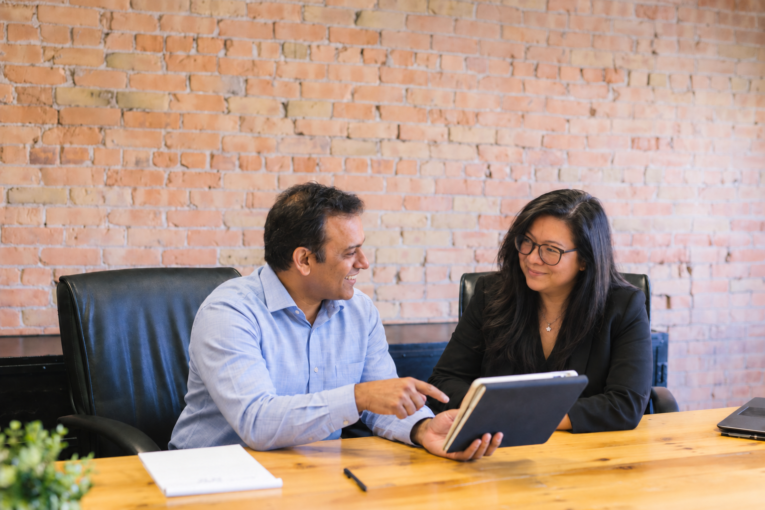 Manish and Laila discussing work at a table